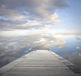 Pontile su acque placide e cielo riflesso